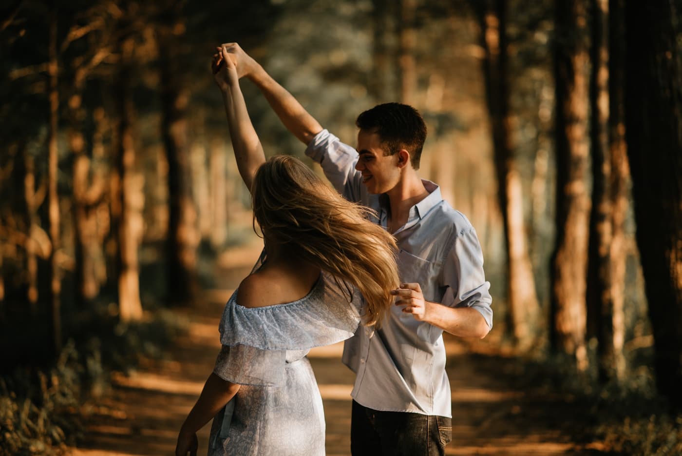 Un couple danse sur un chemin en forêt, dans la lumière du soir